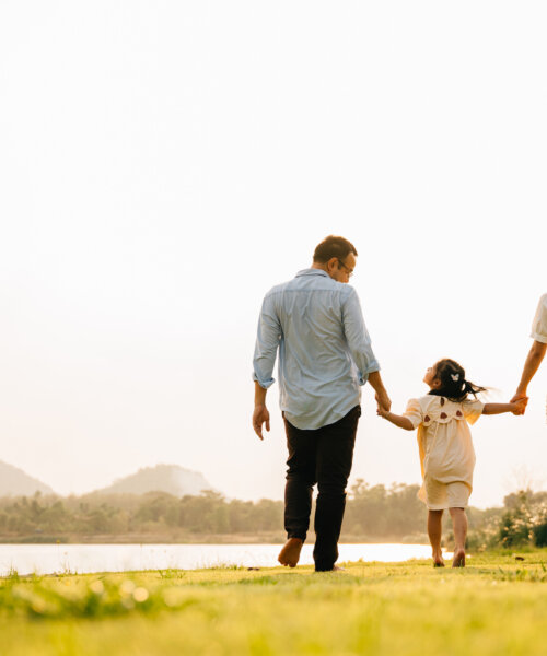 Asian father and daughter walking hand in hand in a scenic garden on a sunny day, enjoying quality time together and the beauty of nature, Family day, back view