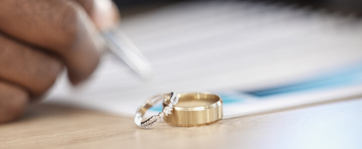 Divorce, rings and signature on paperwork for a lawyer, register wedding or writing on a contract. Table, closeup and a certificate, planning or legal documrnts for a commitment or engagement