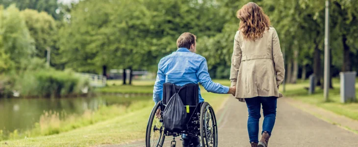Daughter walking with her father in a wheelchair.